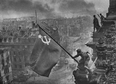 La bandera de la Unión Soviética sobre el Reichstag. Esta foto fue editada por Khaldei para hacerla más dramática y también para ocultar la sugerencia de que en algún momento durante la batalla de Berlín el compañero de Kovalev había saqueado un par de relojes de pulsera que llevaba.